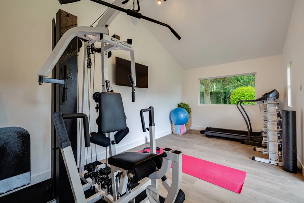 Bright home gym garden room with strength equipment and vaulted ceiling