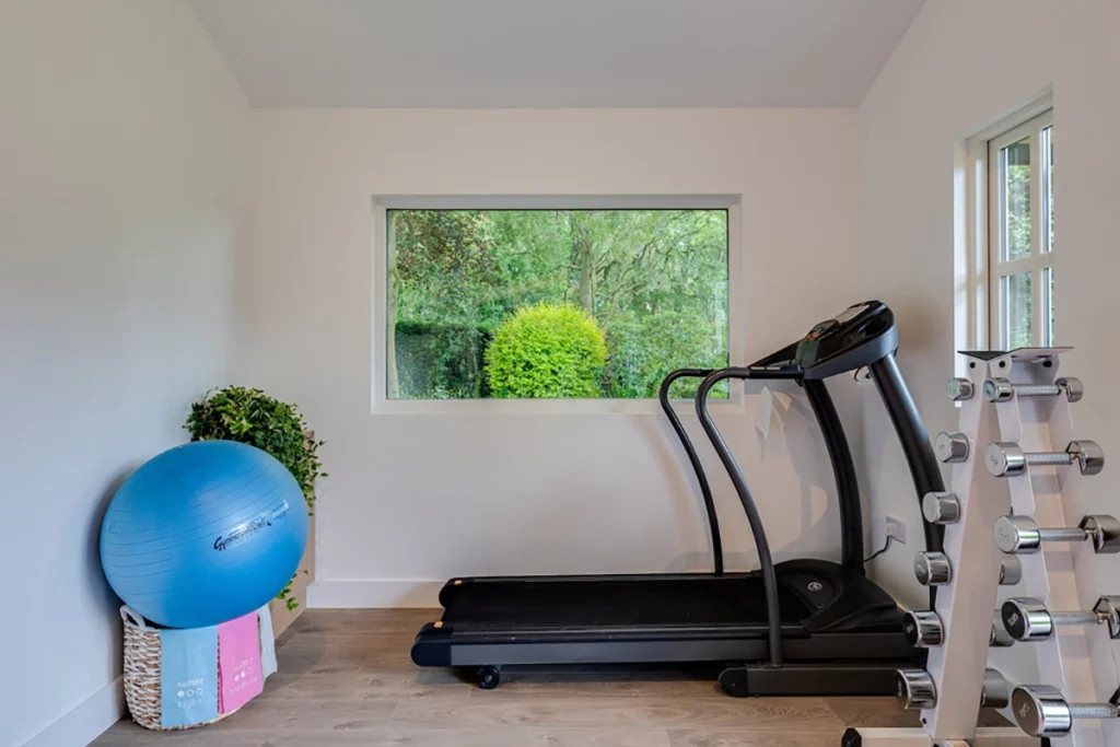 Home gym garden room with treadmill and large window overlooking garden