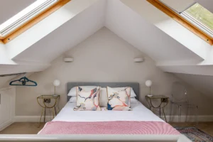 Loft bedroom with rooflights and exposed beams in barn conversion